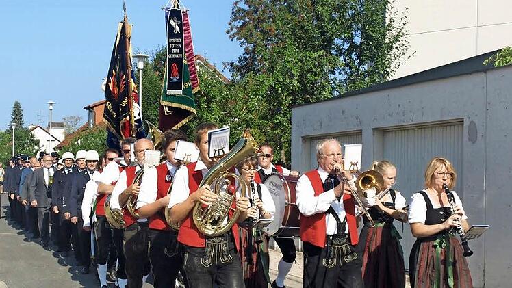 Im Festzug ging es mit Musikkapelle, Fahnenabordnungen, Feuerwehrleuten und Ehrengästen von der Kirche zum Feuerwehrhaus. Fotos: Geiger