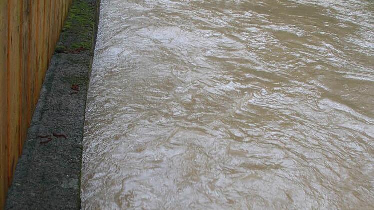 Der Kelbach wurde in Prächting zum reißenden Fluss - Markus, Armin und Erwin Fuß schauen über den Zaun in den Bach, der in der Nacht zuvor das Grundstück überschwemmt hatte. Foto: Matthias Einwag