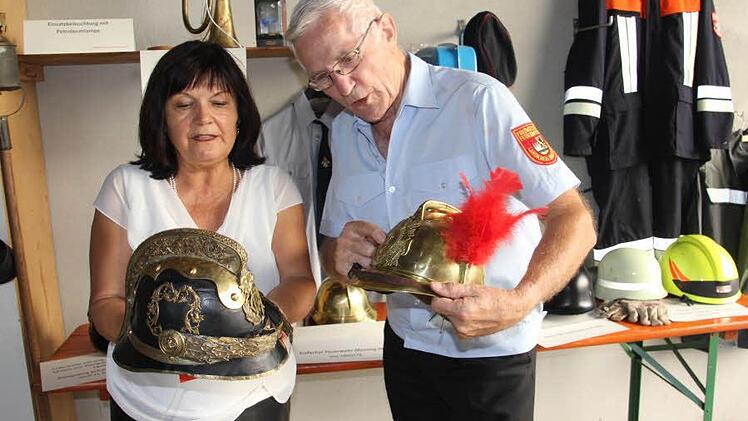 Gertrud Bühl und Ehrenkreisbrandinspektor Reiner Schuster fachsimpeln über alte Helme.