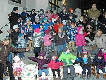 Das erste Fenster des "Begehbaren Adventskalenders", den der Verein "Bibelwelten" Haßfurt heuer zum neunten Mal organisiert hat, öffnete sich am 1. Dezember an der Stadthalle (im Bild). Mit Leib und Seele dabei waren die Kinder der evangelischen Kindertagesstätte sowie (hinten von rechts) die Pfarrer Stephan Eschenbacher und Doris Otminghaus. Foto: Langer