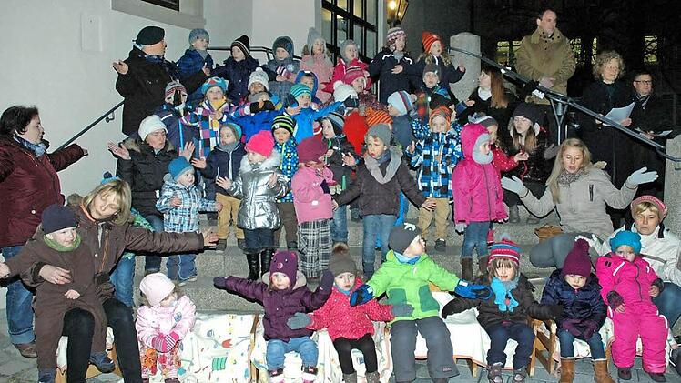 Das erste Fenster des "Begehbaren Adventskalenders", den der Verein "Bibelwelten" Haßfurt heuer zum neunten Mal organisiert hat, öffnete sich am 1. Dezember an der Stadthalle (im Bild). Mit Leib und Seele dabei waren die Kinder der evangelischen Kindertagesstätte sowie (hinten von rechts) die Pfarrer Stephan Eschenbacher und Doris Otminghaus. Foto: Langer