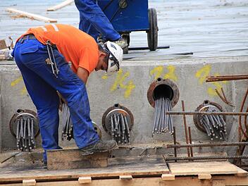 Die im frischen Beton auf der neuen Flutbrücke verlegten Stahlstäbe werden jetzt gespannt. Foto: Andreas Dorsch