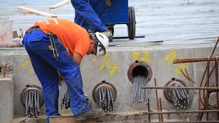Die im frischen Beton auf der neuen Flutbrücke verlegten Stahlstäbe werden jetzt gespannt. Foto: Andreas Dorsch