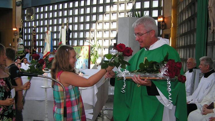 Ein diesjähriges Kommunionkind überreicht eine Rose an Pfarrer Gerhard Möckel.  Foto: Heidi Amon