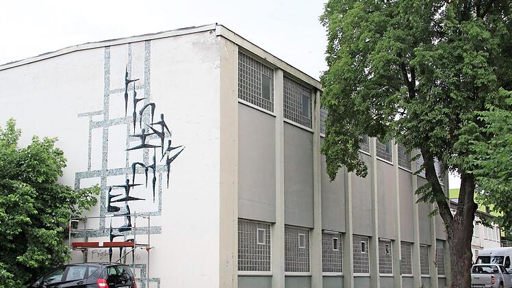 Zwei übereinander liegende Turnhallen stecken in diesem Gebäude, das 1962 gebaut wurde. Jetzt hat es ausgedient. Von dem Mosaik-Kunstwerk an der Stirnseite sollen zwei Figuren gerettet werden.  Foto: Andreas Dorsch