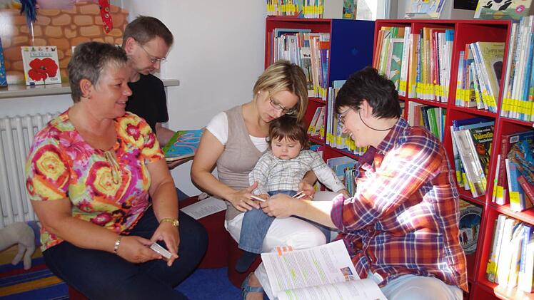 Jan Levi betrachtet auf dem Schoss seiner Mutter Kathrin Günther ein Bilderbuch. Mit im Bild sind (von links) Maria Pestke, Achim Günther sowie Sabine Wank. Das Bild stammt vom ersten Treffen der "Kronacher Büchergeister" im Büchertreff am Melchior-Otto-Platz in Kronach.Foto: Heike Schülein