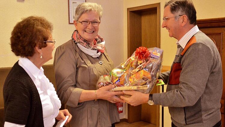 Stellvertretend für die Senioren bedankt sich Irmgart Müller (links) mit einem Präsentkorb bei Angela Metz. Der ist jedoch so schwer, dass Kirchenpfleger Georg Rottenberger als Transporteur aushelfen muss. Foto: Kathrin Kupka-Hahn