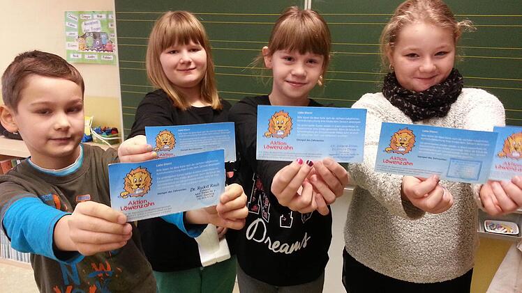 Zwei solcher Löwenzahn-Karten bekommt jeder Schüler für das Jahr, zeigen hier Nick, Nina, Valentina und Jana (von links). Wer beim Zahnarzt war, lässt sie abstempeln und wirft sie in eine Box im Klassenzimmer. Für die 200 Euro Preisgeld von 2014/2015 wurden Pausenspiele angeschafft, berichtet Schulleiterin Katja Prediger.  Foto: Sabine Christofzik