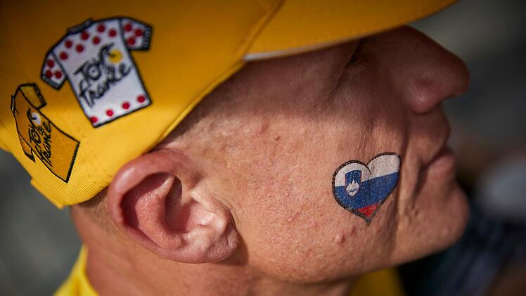 Ein slowenischer Radsport-Fan wartet auf den Champs Elysees auf die Ankunft der Fahrer auf ihrer Schlussetappe der Tour de France. Die könnte 2025 spannend und anders als jemals zuvor werden.