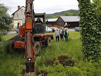 Bernd Wunder vom gleichnamigen Baggerbetrieb gräbt zur Bodenerkundung Erdreich auf dem Grundstück am Langenbühl ab, auf dem die Arztpraxis entstehen soll. Bürgermeister Ralf Holzmann (rechts, Mitte), sein Stellvertreter Fritz Rösch (links daneben) und Ingenieur Hans Spindler verfolgen gespannt, was die Baggerschaufel aus dem Untergrund zu Tage fördert. Foto: Matthias Beetz
