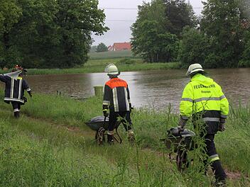 Die Feuerwehrmänner und Feuerwehrfrauen versuchen den Damm des Kübelweihers zwischen Hausen und Heroldsbach mit Sandsäcken zu stabilisieren. Ein Dammbruch würde die Hochwasser-Lage in Hausen dramatisch verschärfen.  Fotos: Nikolas Pelke