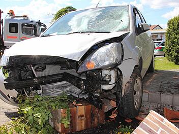 Ein Teil der völlig demolierten Säule hat sich mit dem Grün des Gartens unter dem Unfallfahrzeug verkeilt. Foto: Marco Meißner