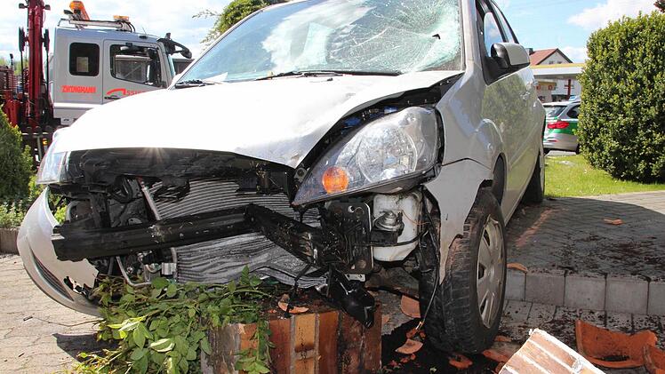 Ein Teil der völlig demolierten Säule hat sich mit dem Grün des Gartens unter dem Unfallfahrzeug verkeilt. Foto: Marco Meißner