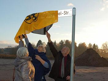 Hellmut Grempels Töchter Brigitte Maaser (links) und Clarissa Kob ziehen gemeinsam mit Oberbürgermeister Frank Rebhan die Fahne der Stadt Neustadt vom Schild für die Straße, die ab jetzt den Namen ihres Vaters trägt. Foto: Rainer Lutz