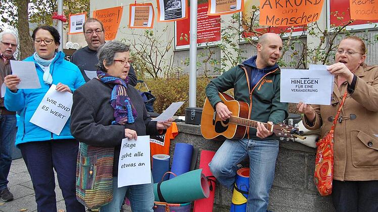 Auftakt mit Gesang: Bevor sich die Demonstranten auf den Boden legten, machten sie unter Leitung von Pflegerin Karin Stratmann (links) mit dem Lied "Deutschlands Pflege liegt am Boden" auf sich aufmerksam