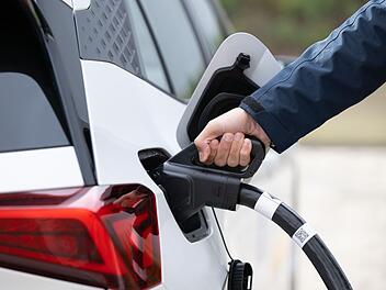 Ein Mann steckt ein Ladekabel in ein Elektroauto