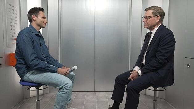 Johann Wadephul (rechts) stellt sich bei "Next Stop K&ouml;ster" den kritischen Fragen von Fabian K&ouml;ster - eingesperrt in einem Fahrstuhl.