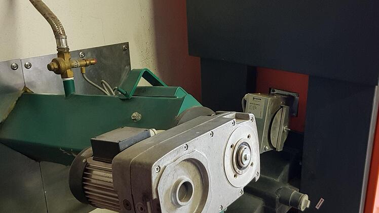 Grün eingehaust ist die Transportschnecke, die die Hackschnitzel aus dem Bunker zieht und für die Verbrennung im Kessel zur Verfügung steht. Das Prinzip ist durchdacht und für alle Fälle gibt es einen eingebauten "Sprinkler" (oben auf der grünen Einhausung). Durch den Schlauch kann im Überhitzungsfall sofort Wasser zufließen und einen Brand im Keim ersticken.