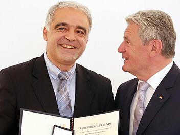 Bundespräsident Joachim Gauck überreicht dem bei Bamberg lebenden Autor Nevfel Cumart im Berliner Schloss Bellevue das Bundesverdienstkreuz. Foto: dpa