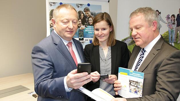 Landrat Thomas Bold (von links), Anja Baniewicz von der DB Regio Bus und Michael Schäder, Nahverkehrsbeauftragter des Kreises, schauen sich die neue Mobilitäts-App an. Die gedruckten Busfahrpläne und die Karte mit dem Wabentarif gibt der Kreis aber trotzdem weiter raus. Foto: Ralf Ruppert