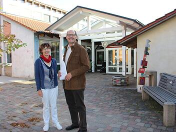 Claudia Straub und Dieter Muth vor dem Kindergarten St. Peter und Paul in Oberleichtersbach: Das Bestandsgebäude wird in Kürze saniert. Der Neubau im hinteren Bereich ist fast fertig. Foto: Julia Raab