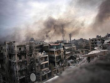 Symbolbild: Rauch über dem zerstörten Saif al Dawle in Syrien. Foto: Maysun, dpa