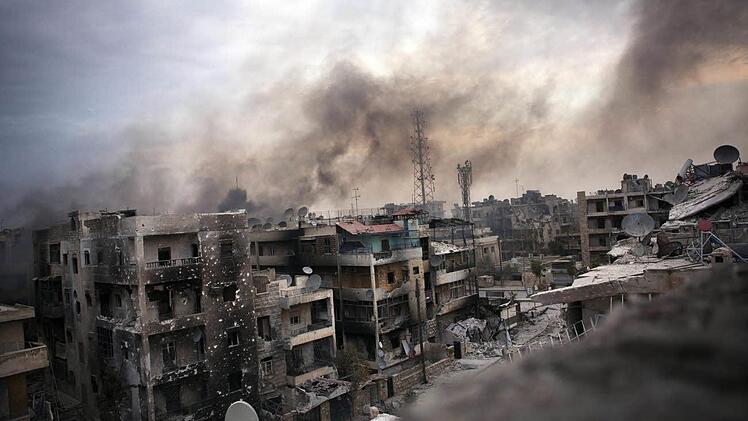 Symbolbild: Rauch über dem zerstörten Saif al Dawle in Syrien. Foto: Maysun, dpa