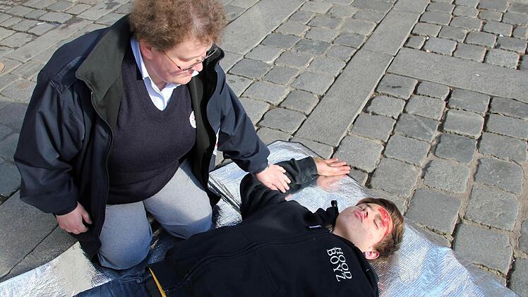 Robin hat eine Kopfplatzwunde an der linken Stirn, deshalb dreht ihn Kerstin Lange auf die rechte Seite in die stabile Seitenlage, damit Robin nicht auf seiner Wunde liegt. Als erstes legt Lange Robins rechte Hand neben seinen Kopf.