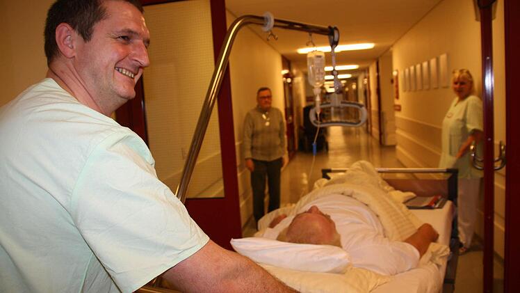 Im zart türkisfarbenen Kittel durch die Krankenhausgänge: Daniel Dittrich gehört zu den Mitarbeitern der Klinikdienste-GmbH. Hier schiebt er einen Patienten zur Untersuchung. Foto: Diana Fuchs