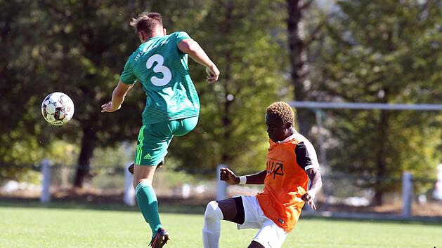Jonas B&auml;uerlein (gr&uuml;nes Trikot) schl&auml;gt den Ball vor dem Kleintettauer Omar Gassama weg.