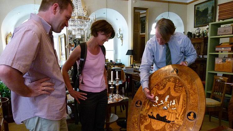Das Erfurter Ehepaar Schlichting l&auml;sst sich von Kunsth&auml;ndler Christian Eduard Franke (rechts) einen h&ouml;fischen Salon-Klapptisch um 1720/25 zeigen.
