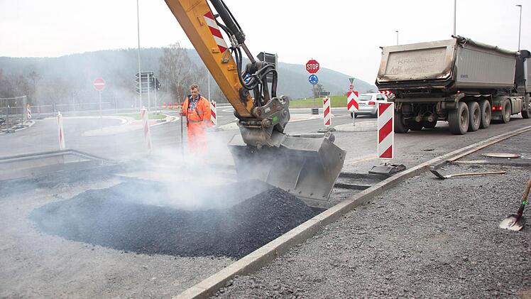 Mit der Baggerschaufel und per Hand wird der Asphalt breit gemacht. Foto: Friedwald Schedel