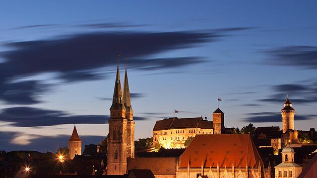 Blick bei Abenddämmerung auf die Altstadt in Nürnberg  mit der illuminierten Kirche St. Sebald  und der Kaiserburg. Foto: Daniel Karmann/dpa