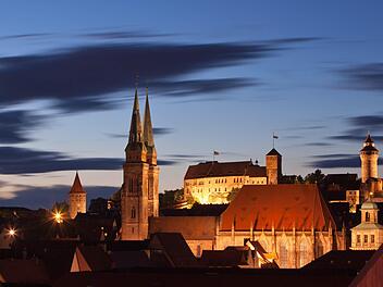 Blick bei Abenddämmerung auf die Altstadt in Nürnberg  mit der illuminierten Kirche St. Sebald  und der Kaiserburg. Foto: Daniel Karmann/dpa