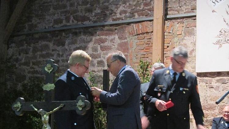 Reinhard Bug bekommt gerade vom stellvertretenden Landrat Emil Müller die Ehrennadel angesteckt, rechts daneben Kreisbrandinspektor Marco Brust. Foto: Diana Leitsch