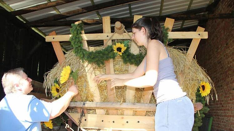 Gerlinde und Sophia Gopp schmücken den Erntewagen, der beim Heimatspiel zum Einsatz kommt. Foto: Heike Beudert