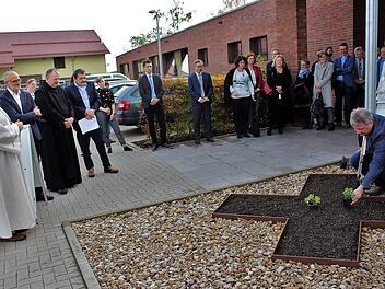 Vor der Fachschule wurde ein Beet in Kreuzform angelegt, in das die Gäste Blumen einsetzten. Im Bild Gremsdorfs Bürgermeister Norbert Walter, Zweiter von links Schulleiter Andreas Keidel, Dritter von links Provinzial Benedikt Hau sowie Gäste aus Politik und Verwaltung. Das langgestreckte Gebäude mit Klinkerfassade ist der neue Erweiterungsbau.      Foto: Evi Seeger