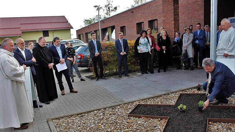 Vor der Fachschule wurde ein Beet in Kreuzform angelegt, in das die Gäste Blumen einsetzten. Im Bild Gremsdorfs Bürgermeister Norbert Walter, Zweiter von links Schulleiter Andreas Keidel, Dritter von links Provinzial Benedikt Hau sowie Gäste aus Politik und Verwaltung. Das langgestreckte Gebäude mit Klinkerfassade ist der neue Erweiterungsbau.      Foto: Evi Seeger