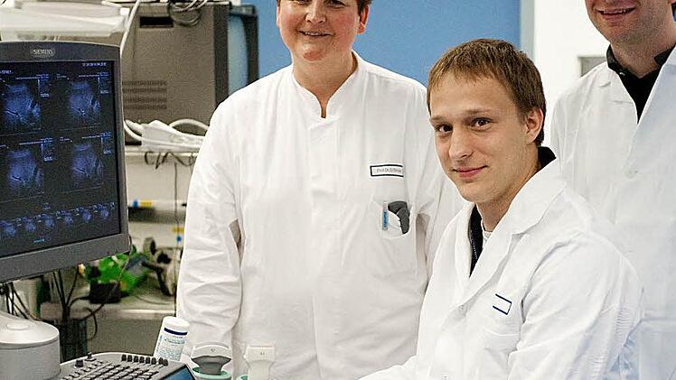 Ferdinand Knieling (sitzend) mit Deike Strobel (Leiterin der Ultraschallabteilung, Medizinische Klinik 1 - Universität Erlangen Nürnberg, Doktormutter) und Maximilian Waldner (Betreuer der Doktorarbeit). Das Bild wurde in der Ultraschallabteilung aufgenommen. Foto: privat