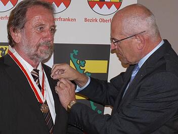 Bezirkstagspräsident Günther Denzler  (r.) heftet Landrat Reinhardt Glauber die Ehrenmedaille des Bezirks Oberfranken an.  Foto: Lp