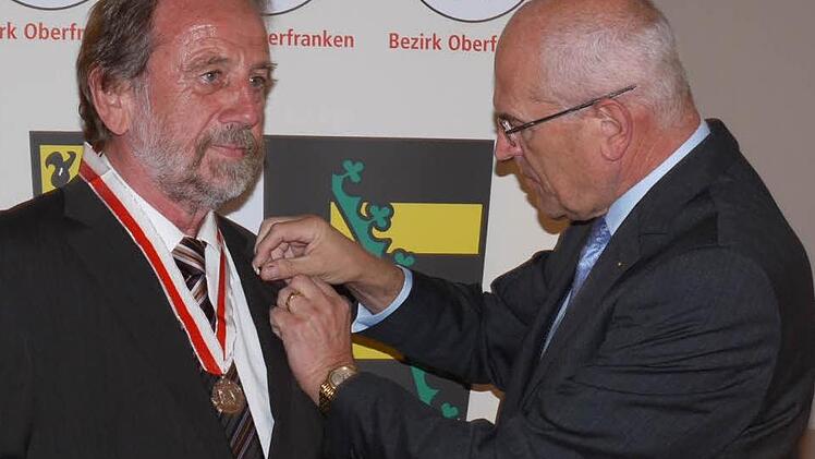 Bezirkstagspräsident Günther Denzler  (r.) heftet Landrat Reinhardt Glauber die Ehrenmedaille des Bezirks Oberfranken an.  Foto: Lp