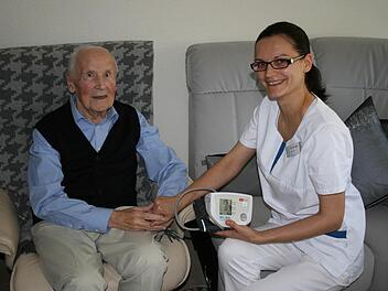 Auszubildende Oxana Schreider vom ambulanten Pflegedienst des Parkwohnstifts kommt regelmäßig zu Bewohner Rudolf Schlagbauer, hier bereitet sie gerade eine Blutdruckmessung vor. Foto: Peggy Raue