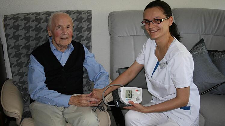 Auszubildende Oxana Schreider vom ambulanten Pflegedienst des Parkwohnstifts kommt regelmäßig zu Bewohner Rudolf Schlagbauer, hier bereitet sie gerade eine Blutdruckmessung vor. Foto: Peggy Raue