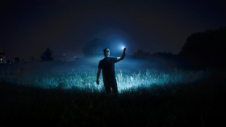 Person with flashlight at night