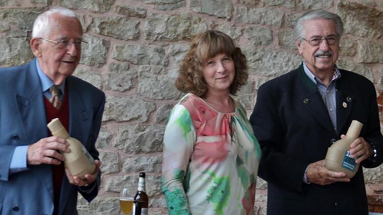 Birgit Merkl vom städtischen Kulturamt überreicht Kreisheimatpfleger Werner Eberth links und Referent Gerhard Wulz, den als Feldflasche gestalteten Erinnerungsbocksbeutel 1866 Foto: Werner Vogel