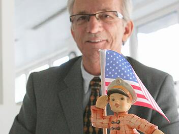 Den kleinen Patrioten hat William Nelson zum Abschied  von  seinem Arbeitgeber, der  Hummel-Manufaktur, bekommen. Die beiden halten die amerikanische Flagge in Ebersdorf hoch. Foto: Christiane Lehmann