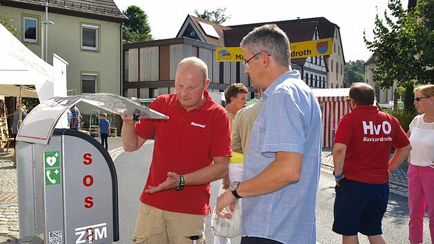 Beim Frühjahrsmarkt 2016 wurde der Defibrillator öffentlich vorgestellt. Inzwischen ist dieser im Schalterraum der Raiffeisenbank montiert. Hier erläutert der Rettungssanitäter Manuel Vorndran Gemeinderat Michael Frank dessen Funktionsweise.  Foto: Kathrin Kupka-Hahn