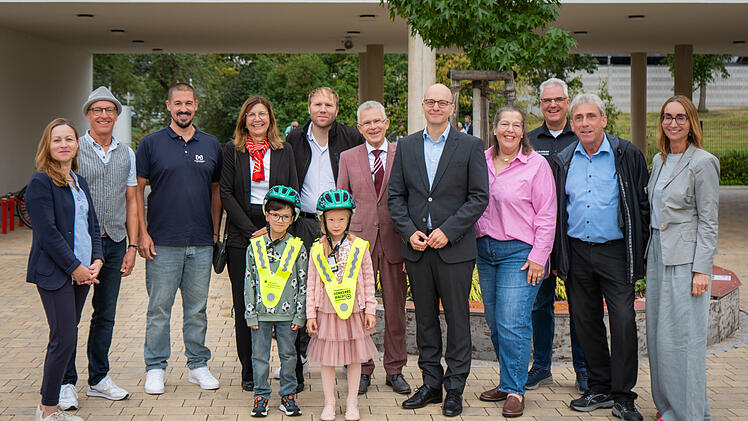 Oberb&uuml;rgermeister Dr. Dirk Vogel (F&uuml;nfter von rechts) &uuml;bergibt gemeinsam mit Vertretern der Bad Kissinger Sponsorenbetriebe Fahrradhelme an die Erstkl&auml;ssler der Sinnberg-Grundschule mit Rektorin Marietta Menz (rechts).