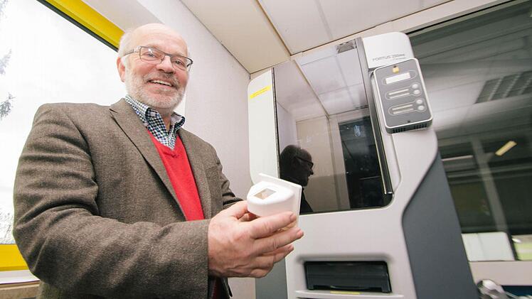 Geschäftsführer Olaf Clausen zeigt das Gehäuse eines Fingerabdruck-Scanners. Hergestellt wurde er mit dem im Hintergrund zu sehenden 3D-Drucker. Foto: Marian Hamacher