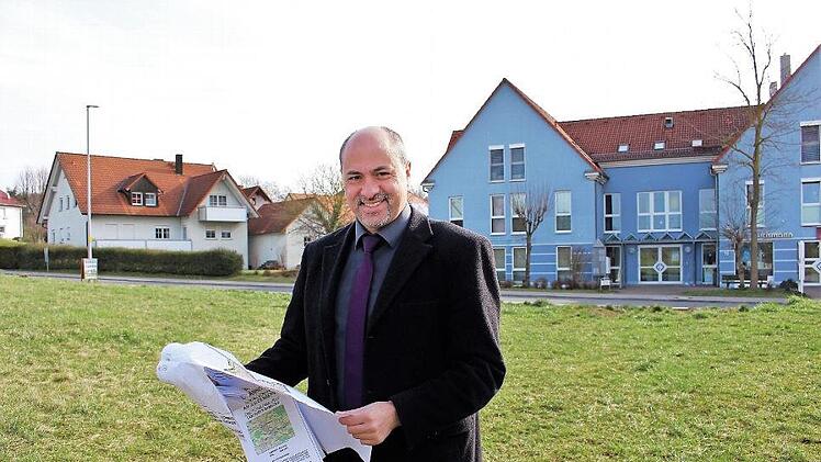 Das Areal an der Bamberger Straße steht nun der Stadt zur Verfügung. In dem blauen Gebäude gegenüber gibt es Ärzte, einen Optiker und eine Bäckerei. Im Bild steht Bürgermeister Johannes Krapp auf dem Baugelände, das die Stadt von den Johannitern gekauft hat. Foto: Evi Seeger